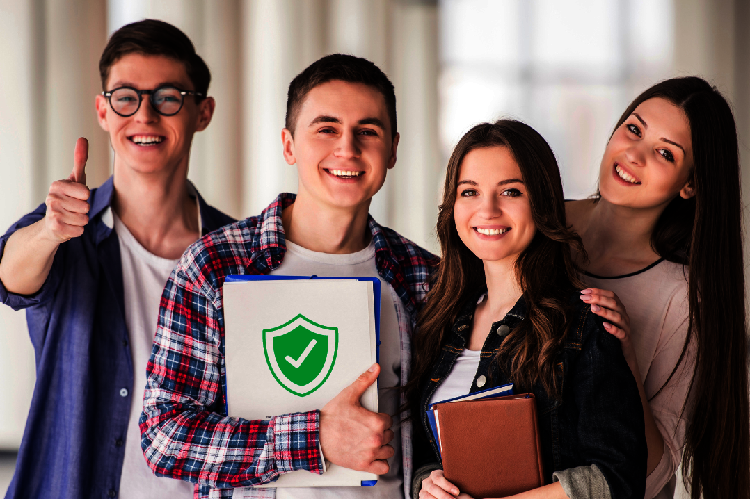 vier junge Studierende lächeln, einer zeigt Daumen hoch